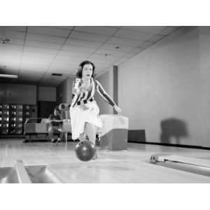 Teenage Girl Releasing Bowling Ball Into Alley, Friend Looking on in 